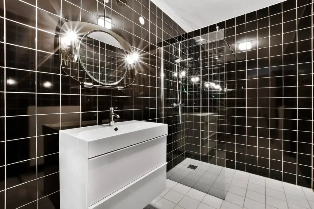 Douche italienne avec paroi vitrée et carreaux de céramique brillants noirs.